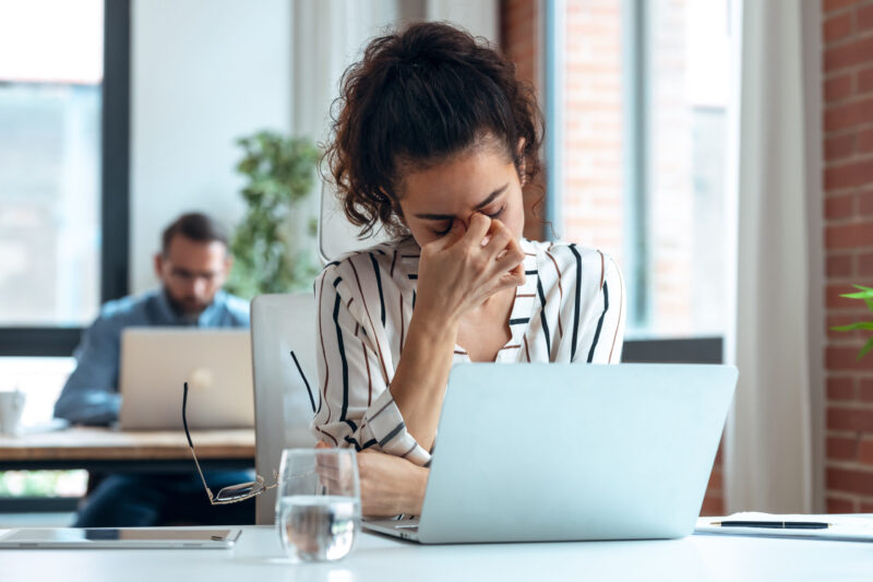 Müde Geschäftsfrau mit Kopfschmerzen am Laptop Müde Geschäftsfrau mit Kopfschmerzen am Laptop